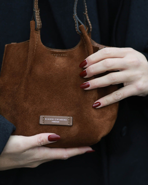 burgundy nails on hands holding bag